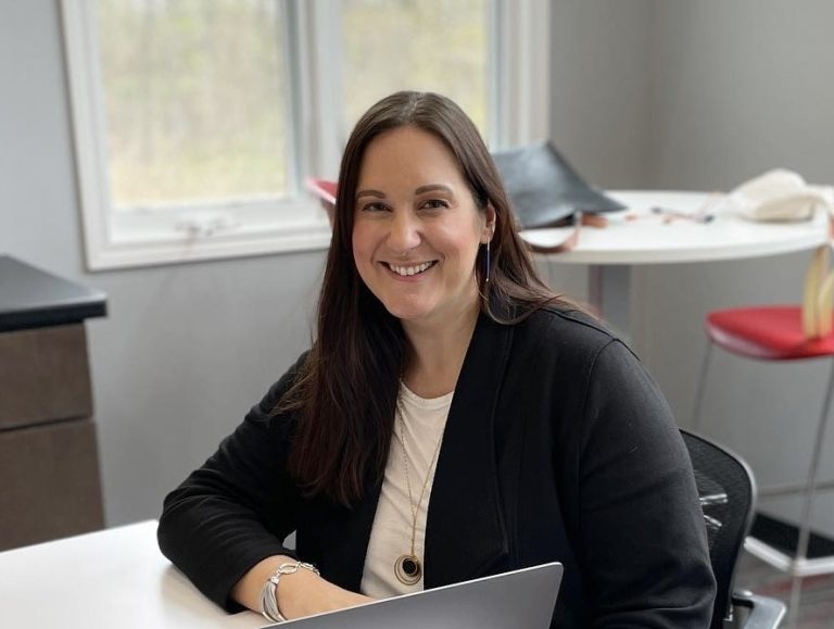 Mary sits at a table, smiling.